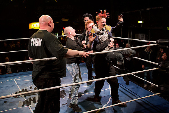 A wrestling fan getting thrown out of the ring